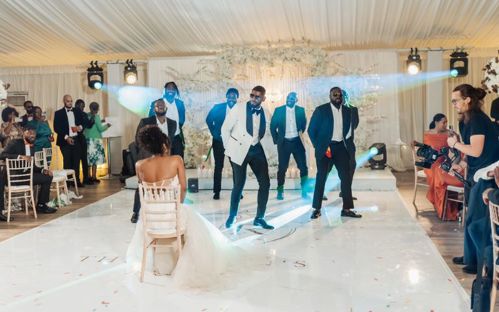 Rochelle sitting on a chair on the dance floor while Andrew and his groomsmen dance.