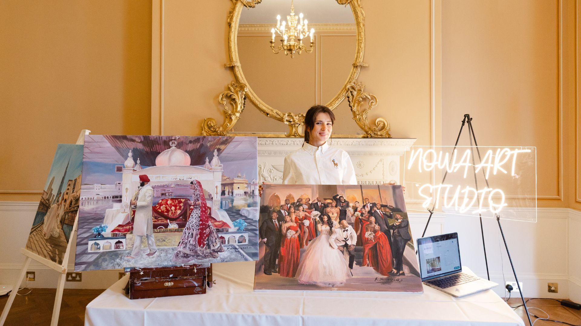 Krystyna from Nowa Art smiling behind a table filled with her paintings. 