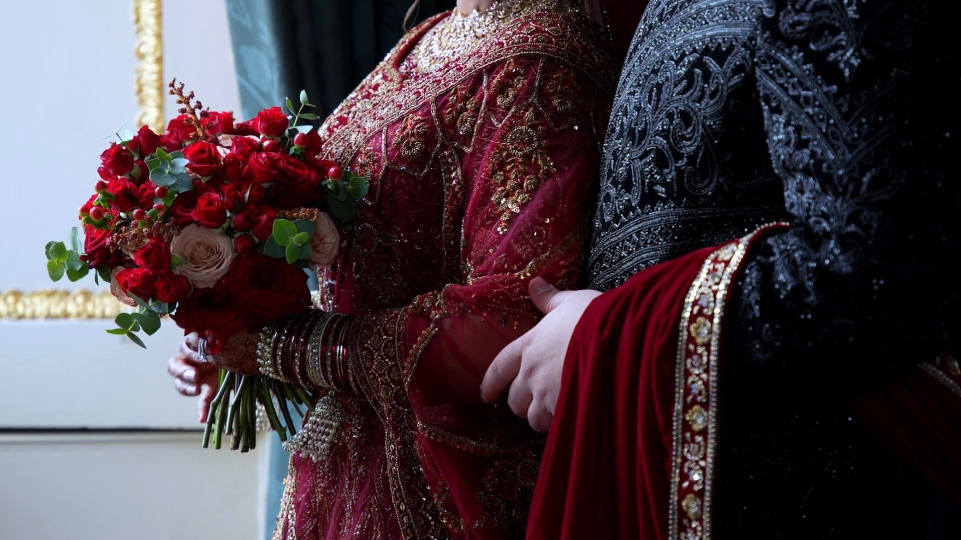 Anika holding her red bouquet while Faisal holds her from behind. 