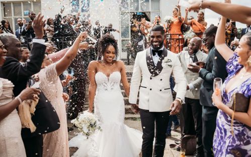 Rochelle and Andrew walking on the East Terrace while friends and family throw confetti at them.