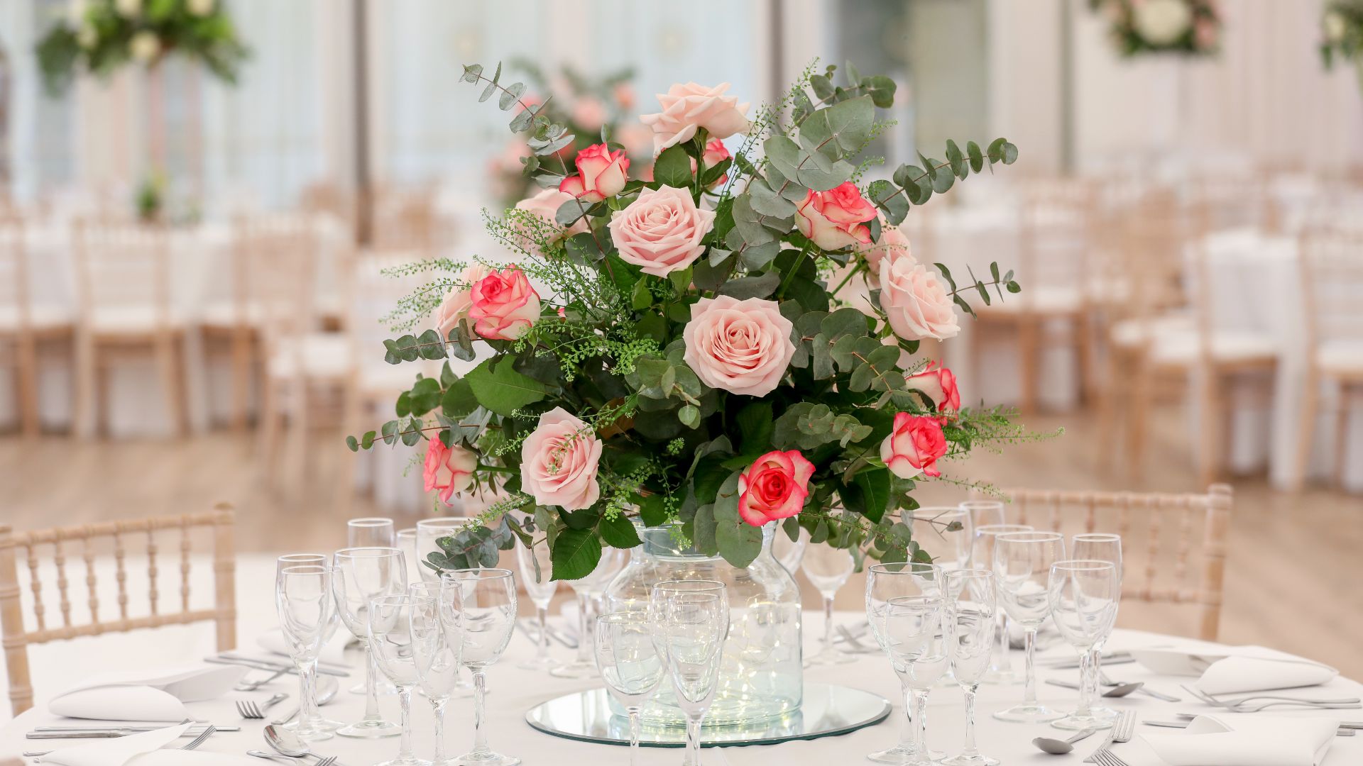 A table with a pink floral centrepiece. 