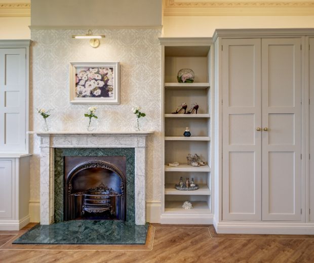 The Rose Room of Hylands House featuring a fireplace and shelves. 