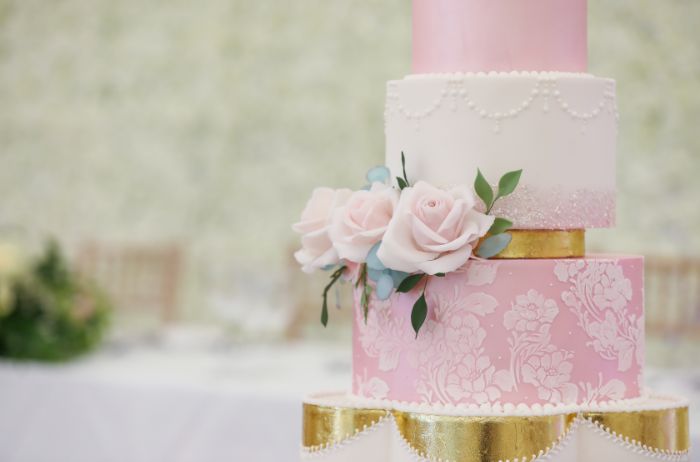 A close up of three tiers of a pink wedding cake. 